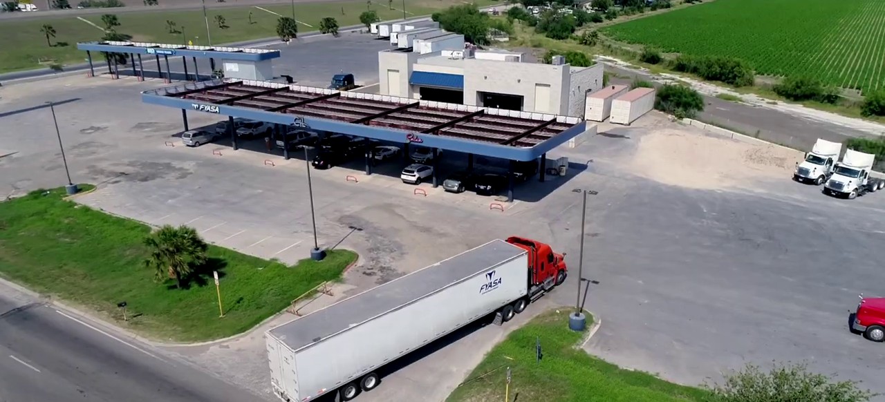 Vista aérea del patio de FYASA en Pharr, Texas, con un tractocamión saliendo con caja de la empresa.